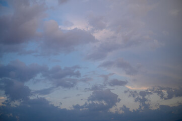 Dramatic clouds drift across a twilight sky, merging shades of blue and gray with hints of golden...