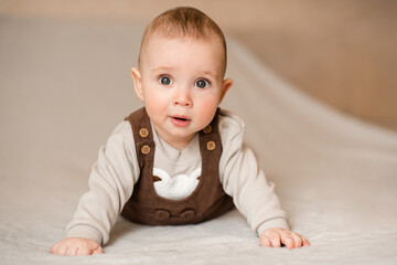 Cute baby boy 3-6 month old crawling in bed looking at camera close up. Childhood.