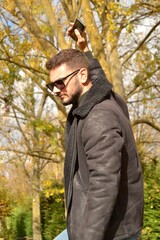 Young handsome guy walking through the park or forest enjoying the autumn. New technologies, mobile phone. Looking for coverage. Taking advantage of free time to read. E-book.Reconnecting with oneself