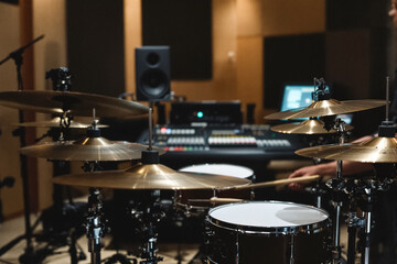Obraz premium A drummer plays on a kit in a soundproof studio, focusing on recording, surrounded by professional equipment