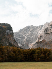 Wundersch&ouml;ne Felswand im Herbst, bunte W&auml;lder im Vordergrund und Bergpanorama im Hintergrund