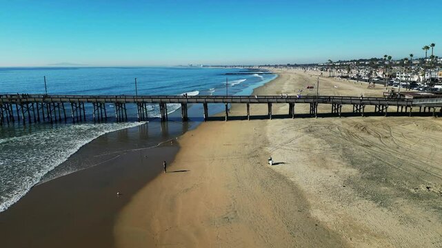 Newport Beach, California, November 20. 2024: New poer Beach, California, In Fall looking at kids at a surfing school on the waves as the drone slides left over the wayer