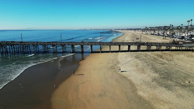 Newport Beach, California, November 20. 2024: New poer Beach, California, In Fall looking at kids at a surfing school on the waves as the drone slides left over the wayer