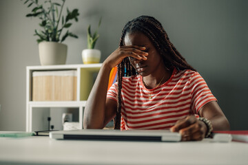 Stressed young woman suffering from headache while working from home office