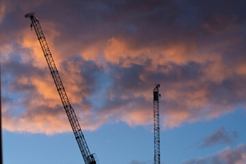 Manchester, United Kingdom, 2024: View of construction crane from a distance, with a blue sky and pink clouds.