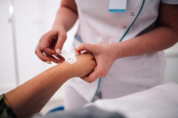 Obraz premium Nurse placing adhesive bandage on patient's arm after injection.