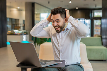 Caucasian bearded businessman working on laptop shocked by sudden victory, game winning lottery...