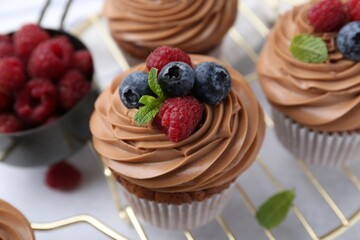Tasty cupcakes with chocolate cream and berries on white table, closeup © New Africa
