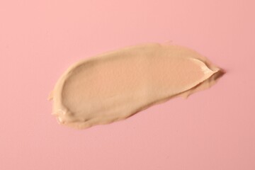 Fototapeta premium Sample of foundation on pink background, top view