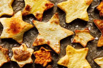 Baked star-shaped potatoes on baking paper, top view. Christmas food idea