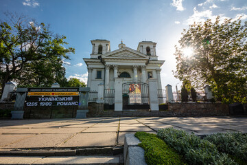 Obraz premium A scenic view of historic churche surrounded by greenery under a vibrant blue sky with scattered clouds. The architecture highlights cultural heritage and peaceful natural surroundings.