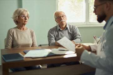 Obraz premium Serious mature couple talking to a doctor in the office. 