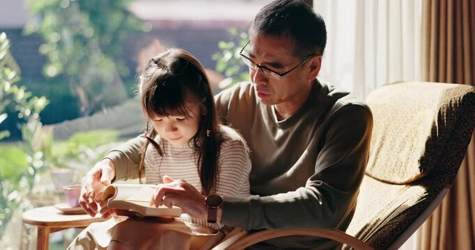 Asian father, child and reading book in family home for learning, education or talk to Japanese girl. Kid, dad and parent storytelling together for help, teaching language or study for development