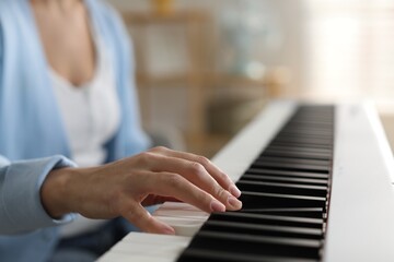 Woman playing synthesizer indoors, closeup. Electronic musical instrument