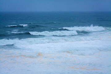 A vast, powerful ocean with rolling waves and white foam stretch