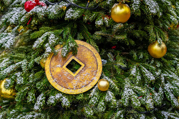 Christmas tree adorned with golden ornaments and large ancient Chinese coin, symbolizing prosperity...