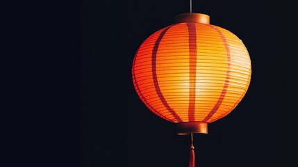 Obraz premium A vibrant orange paper lantern illuminated against a dark backdrop, showcasing delicate patterns and glowing warmly.