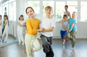 Preteen children learn to dance tango under guidance of a teacher in the ballroom