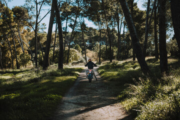 Fototapeta premium Hombre con barba y estilo alternativo con moto de campo en paso de bosque 