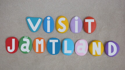 Visit Jamtland, historical province in the centre of Sweden, souvenir composed with multi colored hand painted stone letters over beach sand
