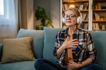 Obraz premium Mature senior woman practice guided meditation manifestation at home