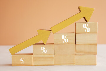 Wooden blocks with percentage sign and arrow up, financial growth, interest rate increase,...