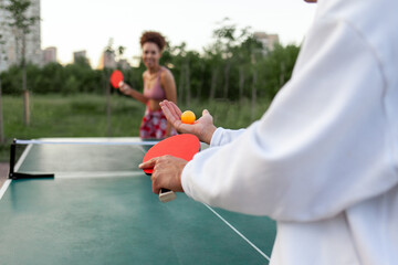 young cheerful african american couple playing table tennis outdoors in the park, woman and man competing as a couple in ping pong and having active rest