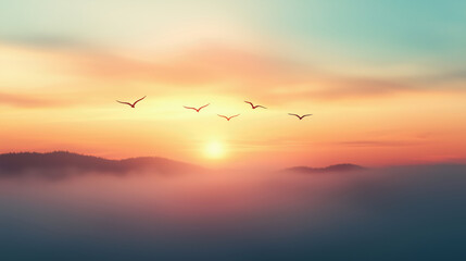 Tranquil sunrise with birds flying over misty mountains