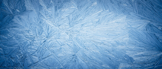 Snowflake frost patterns on glass. Vivid ice crystal textures on clear glass window. Frozen...
