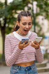 Irritated nervous stressed Caucasian young woman talking screaming on two mobile phones having...