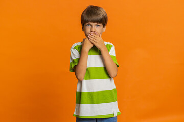 I will not say anything. Frightened strict young preteen child boy kid closing mouth with hands,...