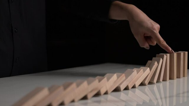Dominoes falling in 4K slow motion, showcasing cascading motion, balance, and the concept of risk management.
