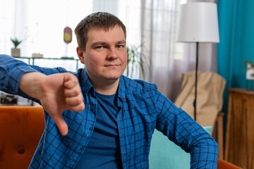Dislike. Upset unhappy young man showing thumbs down sign gesture, expressing discontent,...