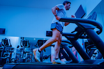 Deportista entrenando en gimnasio sobre cinta de correr.