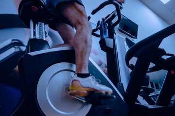 Deportista entrenando en gimnasio sobre bicicleta elíptica.