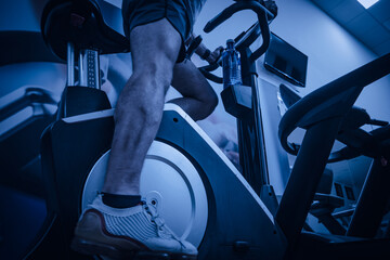 Deportista entrenando en gimnasio sobre bicicleta elíptica.