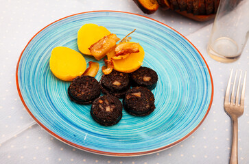 Traditional Spanish blood sausage slices with rice served with baked potatoes..