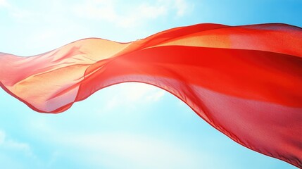 Vibrant red flag gracefully billowing in the breeze against a bright blue sky, capturing the movement and light with a soft, flowing texture.