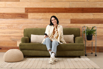 Obraz premium Pretty young woman chatting with mobile phone and resting on green couch at home
