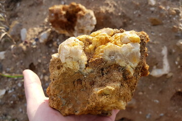 Fragment of a large quartz secretion in hand, searching for mineral samples