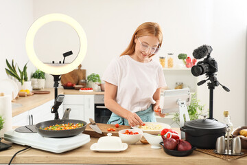 Female food blogger cooking pasta while recording video class in kitchen