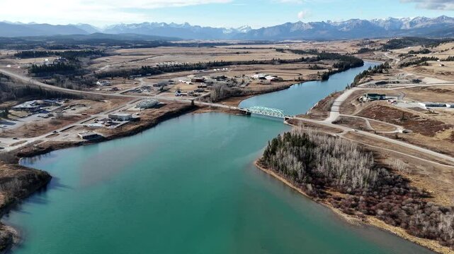 River bridge aerial video overlooking Morley Alberta with Canadian Rockies at background while driving to Banff Canada.
