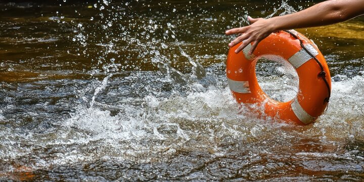 An action shot of a person throwing a life preserver to someone in the water, emphasizing rescue and aid.
