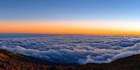 An elevated perspective above the clouds at sunrise, with a glowing orange sky and peaceful cloud cover below.