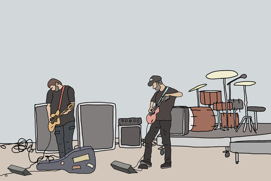 Two male guitarists wearing dark coloured clothing warming up before a gig with drums and speakers