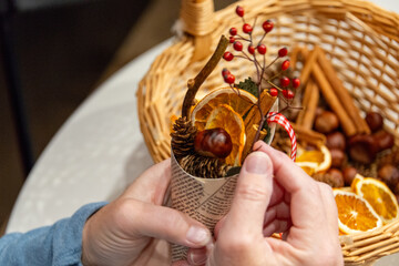 A woman is holding a vintage cone-shaped Christmas decoration. There are supplies of dried orange...