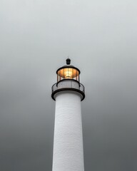 A tall white lighthouse stands against a moody sky, its light glowing brightly, guiding sailors through fog and darkness.