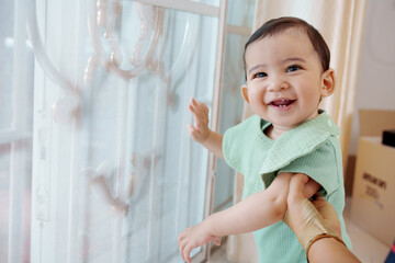 Adorable happy baby playing with kids toys at home while sitting on floor in living room.