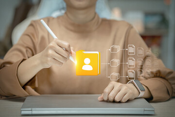 A woman is using a stylus to draw a yellow icon on a laptop screen