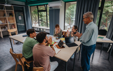 A diverse group of college students collaborate on a project with guidance from an elderly...